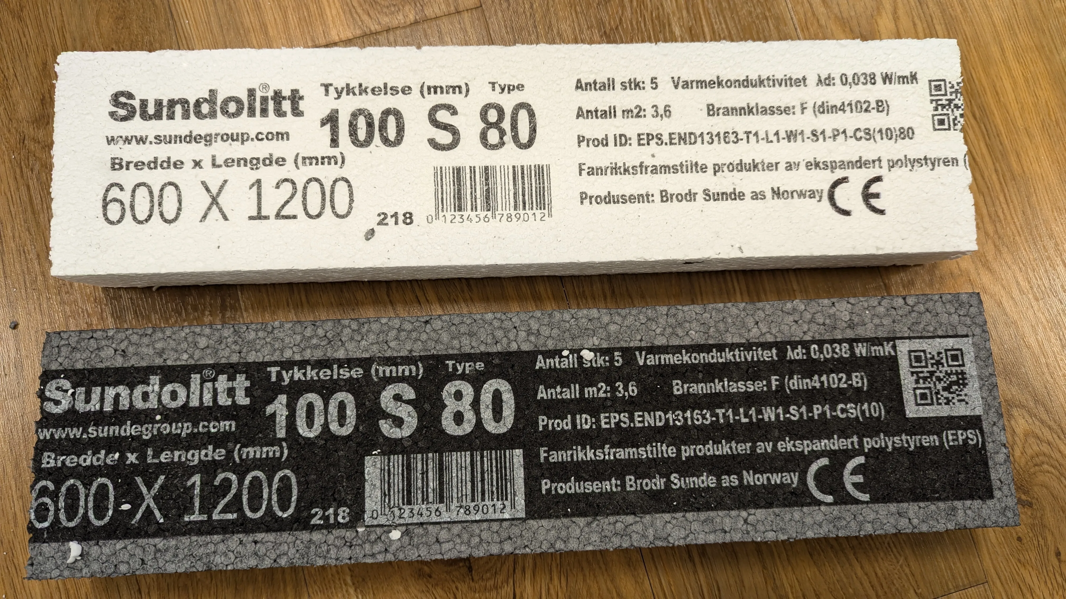 Vit och grå EPS-isoleringsskiva från Sundolitt med CE-märkning, beteckningskod, värmekonduktivitet, QR-kod och streckkod, med vitt tryck på den grå skivan