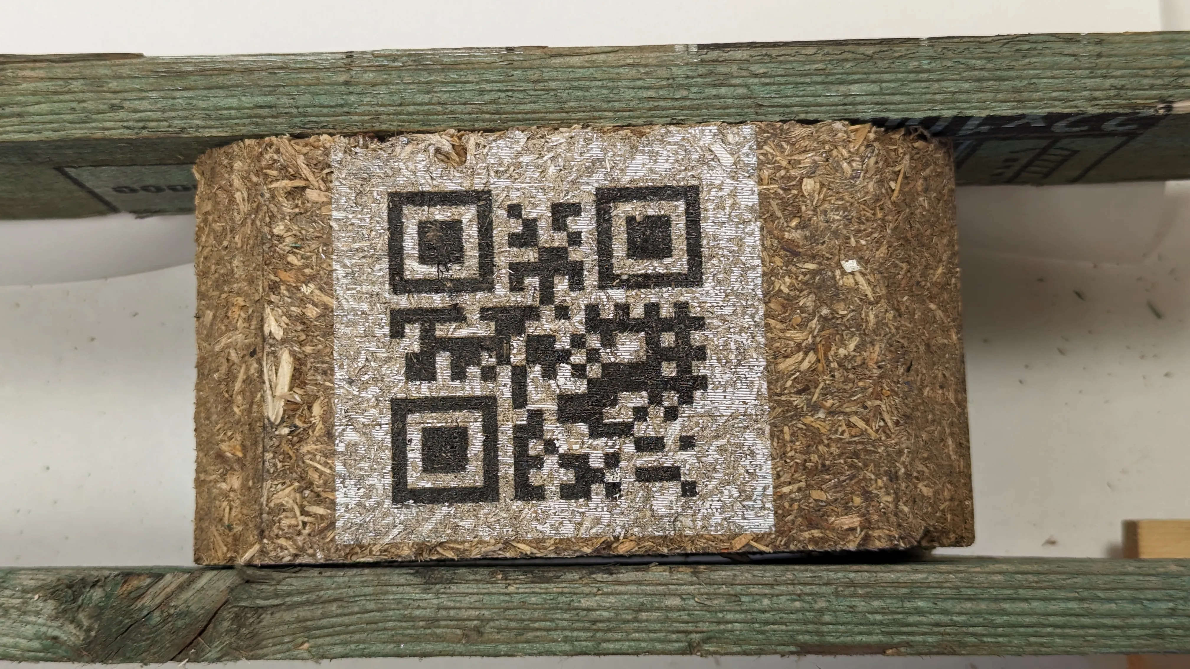 QR-kod i svart på vit bakgrund tryckt på mörk fiberkloss
